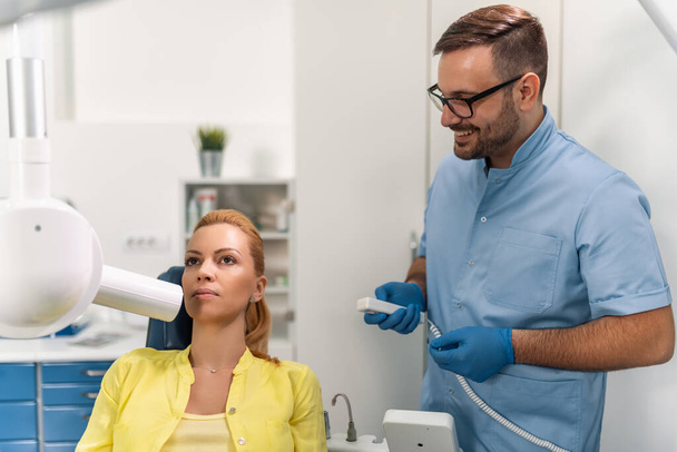 Οδοντίατρος προετοιμάσει για να κάνει το δόντι x-ray εικόνα για τον ασθενή στην οδοντιατρική κλινική.Άνθρωποι, ιατρική, στοματολογία και την υγειονομική περίθαλψη έννοια. - Φωτογραφία, εικόνα