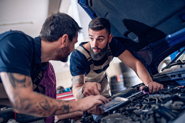 Männliche Mechaniker Reparatur Auto-Motor, verwenden Sie digitale Tablette. - Foto, Bild