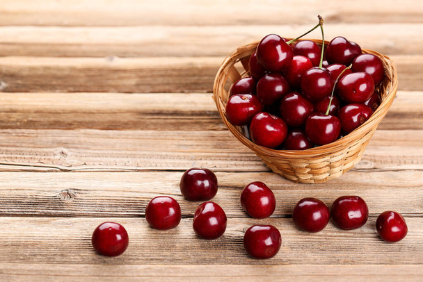 Sweet cherries in basket on brown wooden table - Φωτογραφία, εικόνα