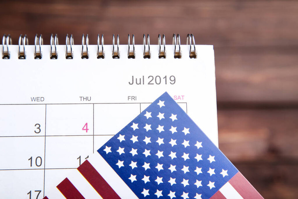 Text Independence Day in calendar with american flag on brown background - Foto, Imagem