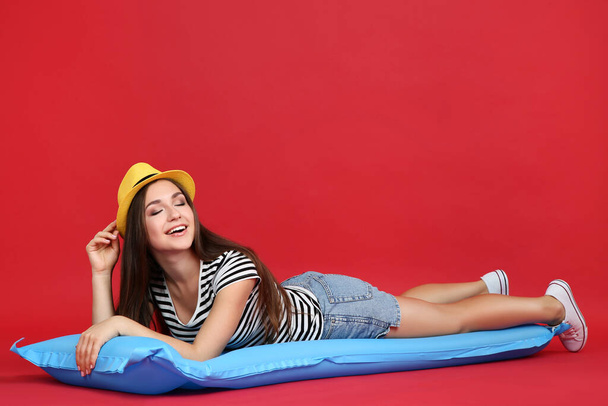 Young girl lying on inflatable mattress on red background - Фото, изображение