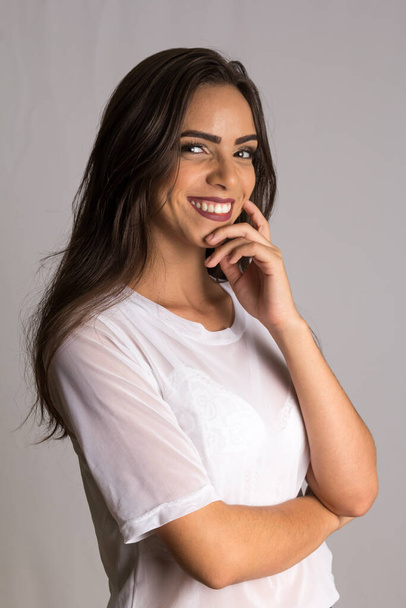 Εσωτερικό πορτρέτο της Βραζιλίας νεαρή μελαχρινή μοντέλο με τα χέρια σταυρωμένα και χαμογελώντας με αυτοπεποίθηση. - Φωτογραφία, εικόνα