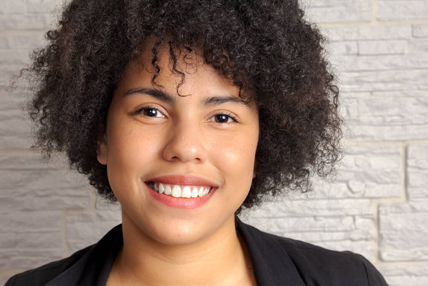 Nahaufnahme Porträt einer jungen schwarzen Frau mit Afro-Frisur, die in die Kamera lächelt. - Foto, Bild