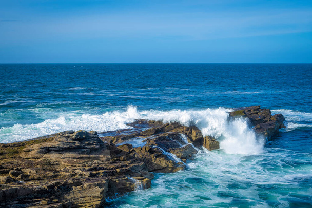 Ocean waves breaking on stone coast in Ireland - Foto, afbeelding