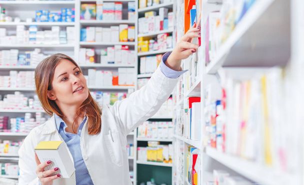 Gyógyszerész ellenőrzi a gyógyszert a gyógyszertár polcain. - Fotó, kép