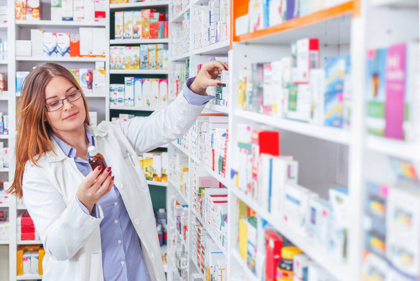 Pharmacist checking a medicine on shelves in a pharmacy drugstore - Photo, Image