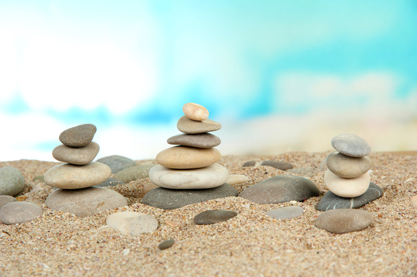 Towers of sea stones on sand on bright background - Foto, Imagen