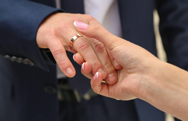 The bride holds the hand of the groom with a gold, engagement ring - Fotoğraf, Görsel