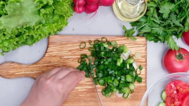Белая женщина режет свежий зеленый лук и готовит салаты
 - Кадры, видео