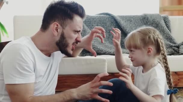 A kislány az apjával játszik. Ijesztő és vicces pózokat csinál. - Felvétel, videó