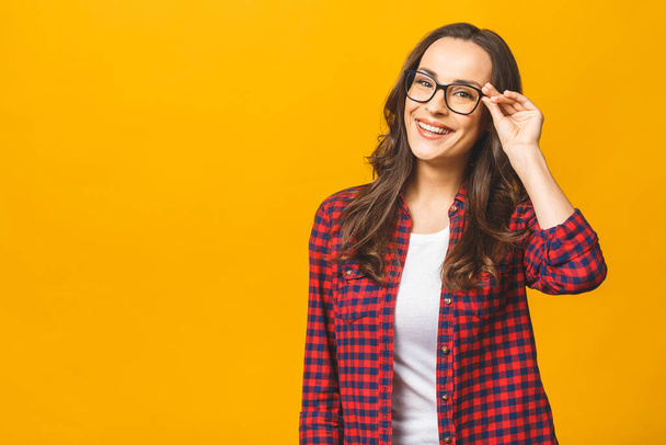 Portrait of a pretty smiling woman in casual and glasses posing isolated on a yellow background. - Valokuva, kuva