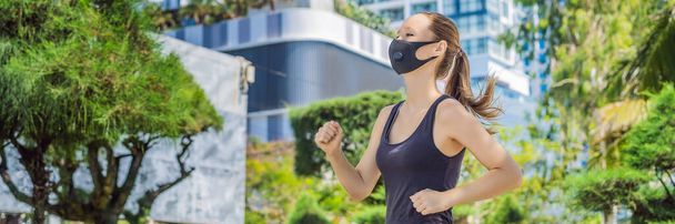 BANNER, LONG FORMAT Woman runner wearing medical mask. Running in the city against the backdrop of the city. Coronavirus pandemic Covid-19. Sport, Active life in quarantine surgical sterilizing face - Photo, image