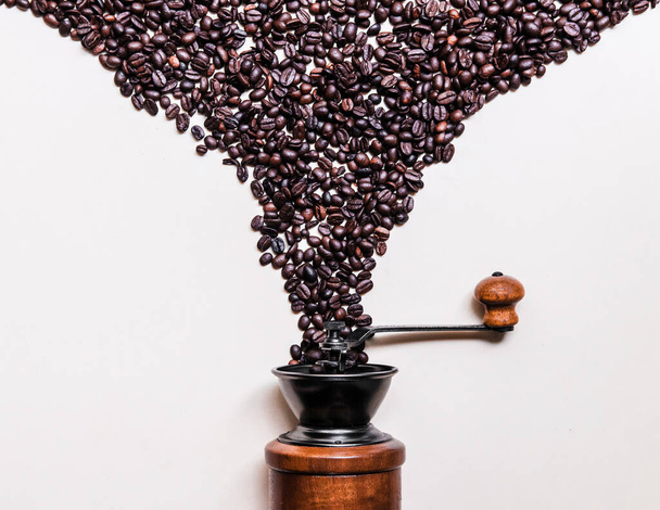 Roasted black Coffee beans dropping into retro wooden grinder at image center islotaed on white background copy space for commercial design work - Photo, Image