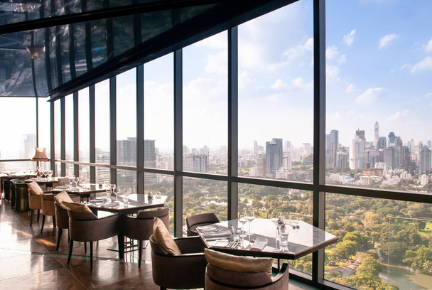 AUG 26, 2013 Bangkok, Thailand - Art deco interior dining room, vibrant desingn with glass wall Bangkok city center view, luxury diner table set and armchairs - Photo, Image