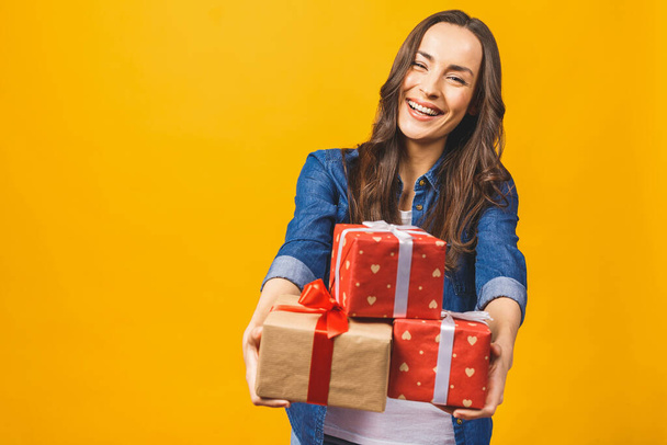 mooi jong brunette meisje holding een cadeau in haar handen en glimlachen tegen de witte achtergrond. - Foto, afbeelding