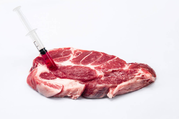 Hormon vagy antibiotikummal szennyezett hús - Vegyi anyag befecskendezése nyers vörös húsba fehér alapon izolált fecskendővel - Egészségtelen élelmiszeripar - Fotó, kép