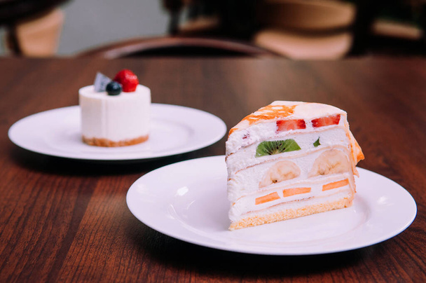 Κρεμώδες κέικ κρεμ με ανάμεικτα φρούτα, φράουλα, ακτινίδιο, μπανάνα σε λευκό πιάτο στο bekery cafe - Φωτογραφία, εικόνα