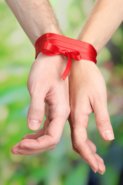 Mans and girls hands tied with ribbon on bright background - Photo, image