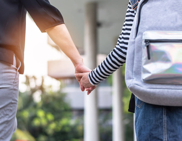 Educational back to school, parent's day, bring kid to work concept with elementary student girl carrying backpack holding woman or mother's hand walking up admission office building going to class - Photo, Image
