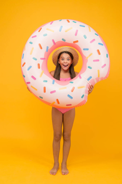 Swimming and sunbathing. Rest at seaside. Pool party. Happy childhood. Entertainment concept. Little girl and swimming donut ring. Kid in swimsuit having fun water activities. Summer vacation - 写真・画像