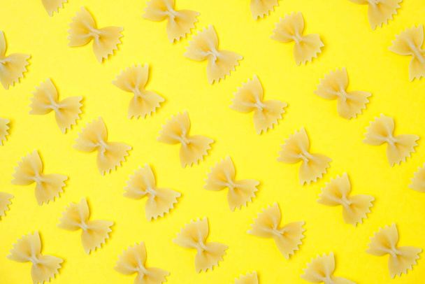 Primo piano modello di noodles farfalle noto anche come papillon o pasta farfalla posto su sfondo giallo. - Foto, immagini