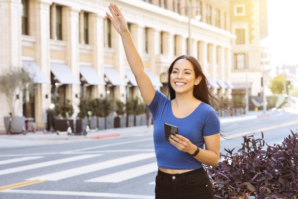 Młoda kobieta koloru macha ręką, aby nazwać udział jazdy w mieście - Uber - Lyft - Daytime - Zdjęcie, obraz