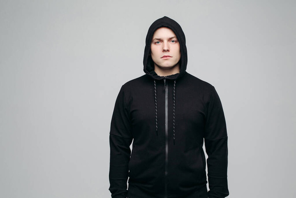 Serious athletic man in black hoodie. Concept of male fashion and look. - Photo, Image