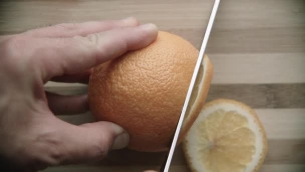 Slicing ripe orange on a cutting board - Filmati, video
