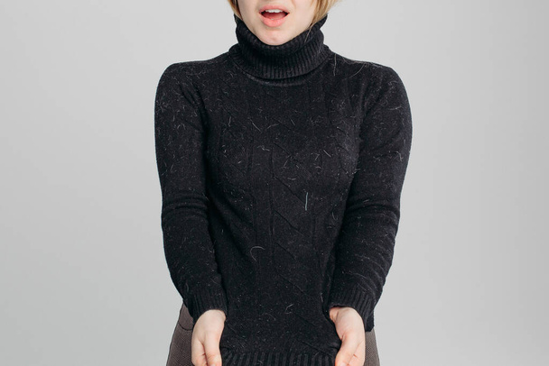 Schockierte Frau zeigt ihren schmutzigen schwarzen Pullover vor der Kamera. - Foto, Bild