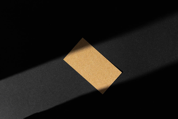 Single businesscard with copy space on black background. Photo with shadow - Φωτογραφία, εικόνα