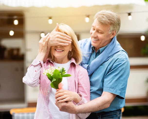 Любящий взрослый мужчина дарит букет полевых цветов своей любимой жене возле дома на колёсах
 - Фото, изображение