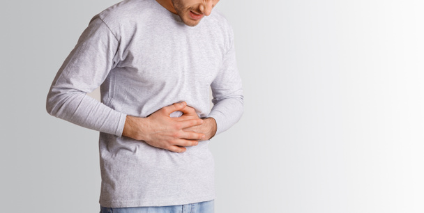 Stomach problems. Man presses his hands to stomach in pain - Photo, Image