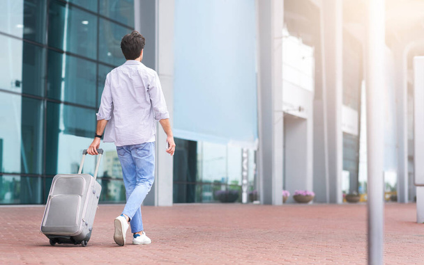 Retrato retrovisor del hombre caminando fuera del aeropuerto con la maleta
 - Foto, Imagen