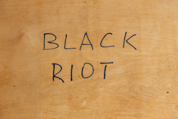 Слова чорного бунту, написані вручну чорним маркерів фарби на плоскій фанерній поверхні. Концепція
. - Фото, зображення