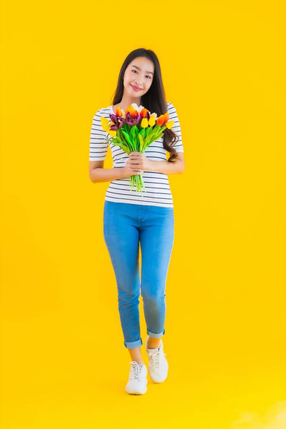 Portrait beautiful young asian woman with colorful flower on yellow isolated background - Foto, Imagem