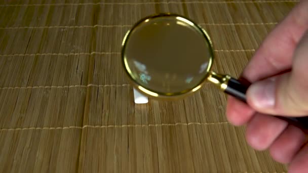 Considers gum under a large magnifying glass in a collection of two pieces - Кадры, видео