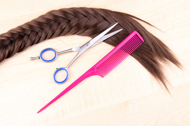 Long brown hair with comb and scissors on wooden background - Photo, image