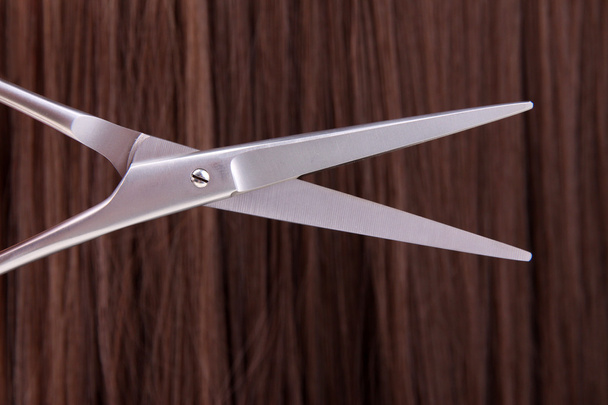 Long brown hair with scissors on close up - Fotografie, Obrázek