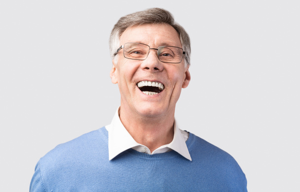 Anciano riendo en voz alta posando sobre fondo gris
 - Foto, imagen