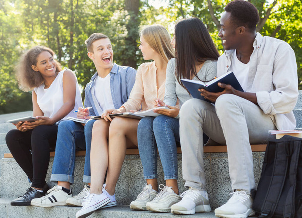 Primer plano de grupo amistoso de estudiantes que estudian al aire libre
 - Foto, imagen
