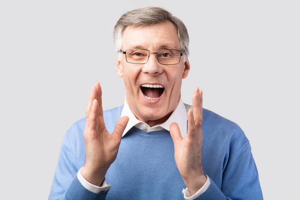 Emocionado caballero mayor gritando posando sobre fondo gris
 - Foto, Imagen