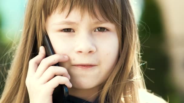 Portret van een mooi meisje met lang haar dat praat op een mobieltje. Kleine vrouwelijke kind communiceren met behulp van de smartphone. Communicatieconcept kinderen. - Video