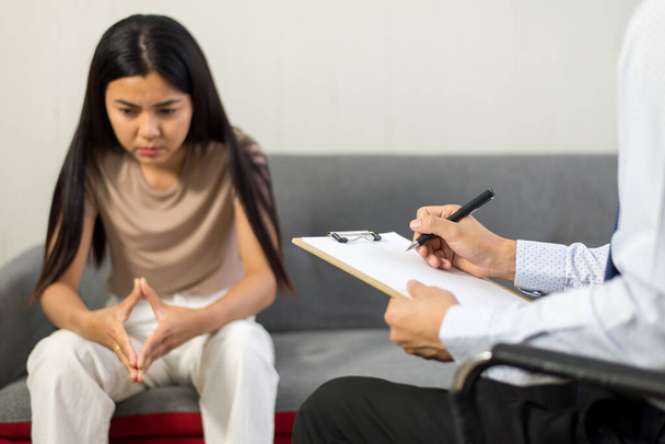 Professional psychologist talking with asian woman patient and writing notes,Therapist conducting a consultation and counseling to women - Foto, imagen