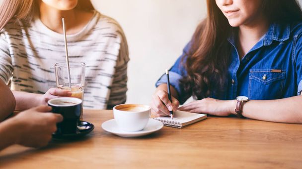 Žena píše na notebook, zatímco pije kávu s přáteli - Fotografie, Obrázek