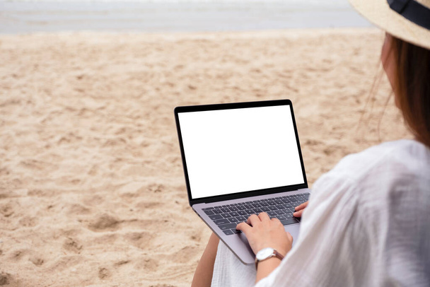 Plaj sandalyesinde otururken dizüstü bilgisayarında boş ekran kullanan ve daktilo kullanan bir kadının görüntüsü.  - Fotoğraf, Görsel