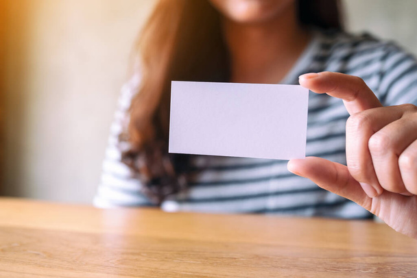 A woman holding and showing a blank empty business card - Photo, Image