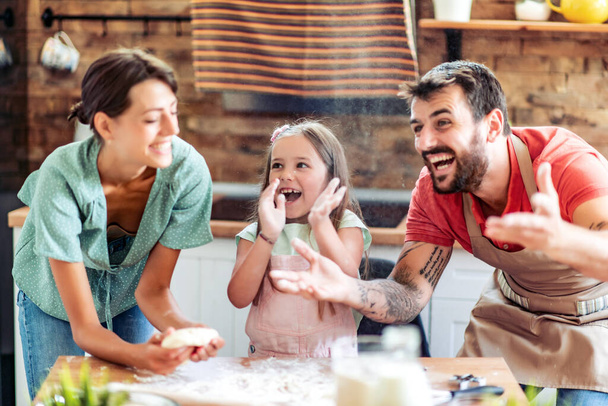 Счастливый отец, Мэзер и дочь, играя с тестом, пекут тесто дома. - Фото, изображение
