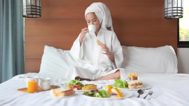 felvétel gyönyörű ázsiai nő reggelizik az ágyban a szállodában - Felvétel, videó