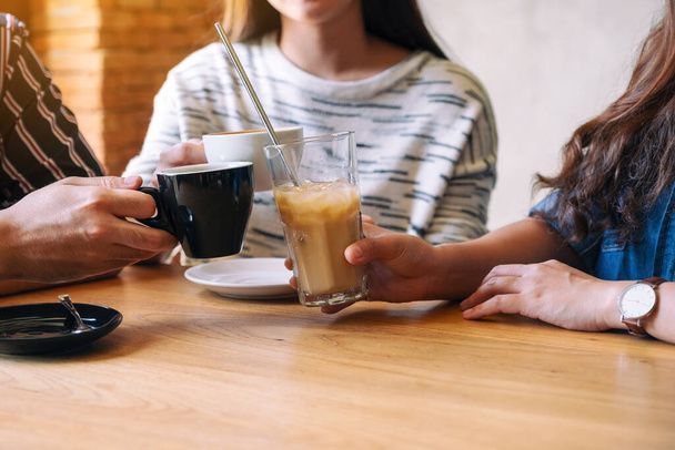 Closeup image of three people enjoyed talking and drinking coffee together in cafe - Photo, Image