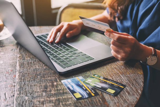 Eine Frau hält Kreditkarten in der Hand, während sie Laptop benutzt - Foto, Bild